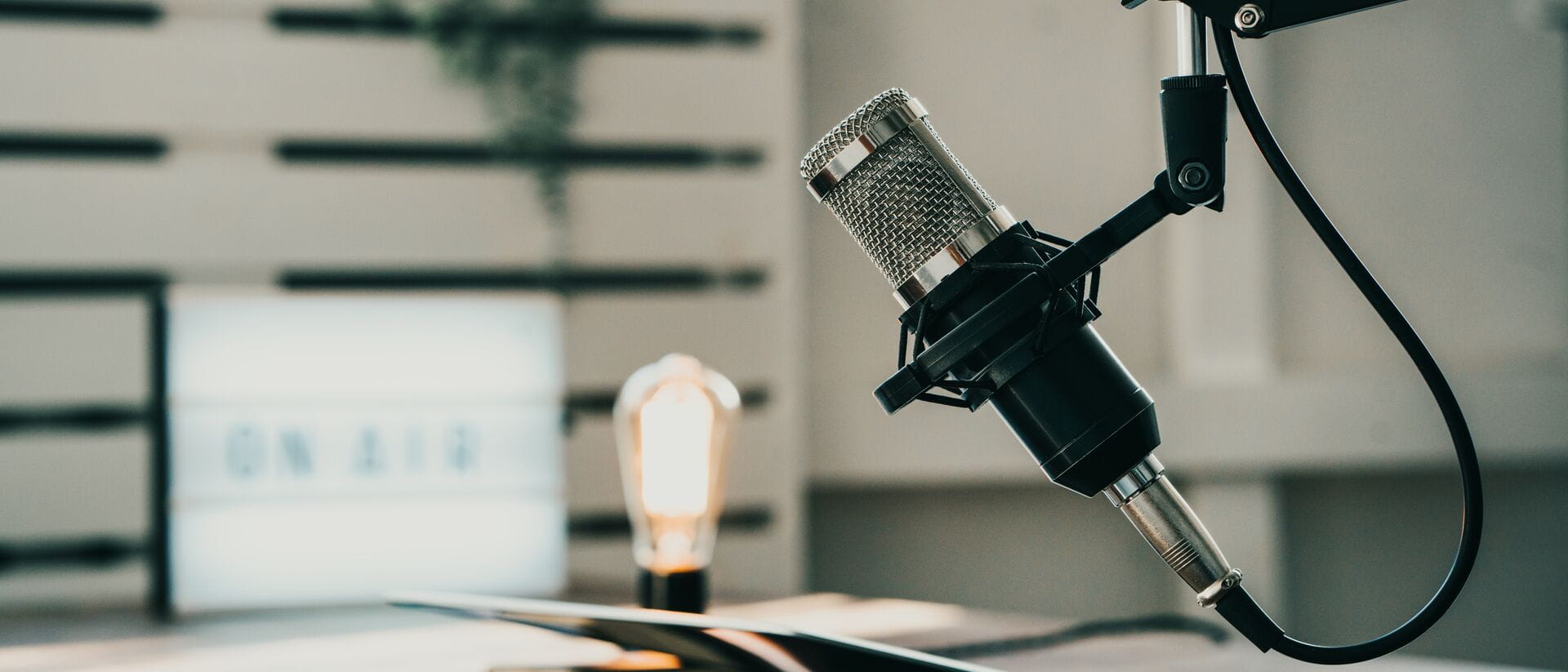 Home studio podcast interior. Microphone, laptop and on air lamp on the table